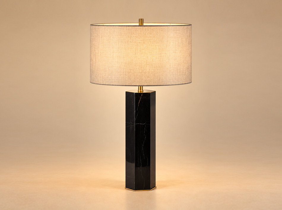 Yuri brushed gold table lamp with tall geometric Black Marquina marble base, delicate natural veining and circular light brown linen shade.